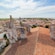 A terracotta tiled rooftop with stone ruins overlooking a waterfront village